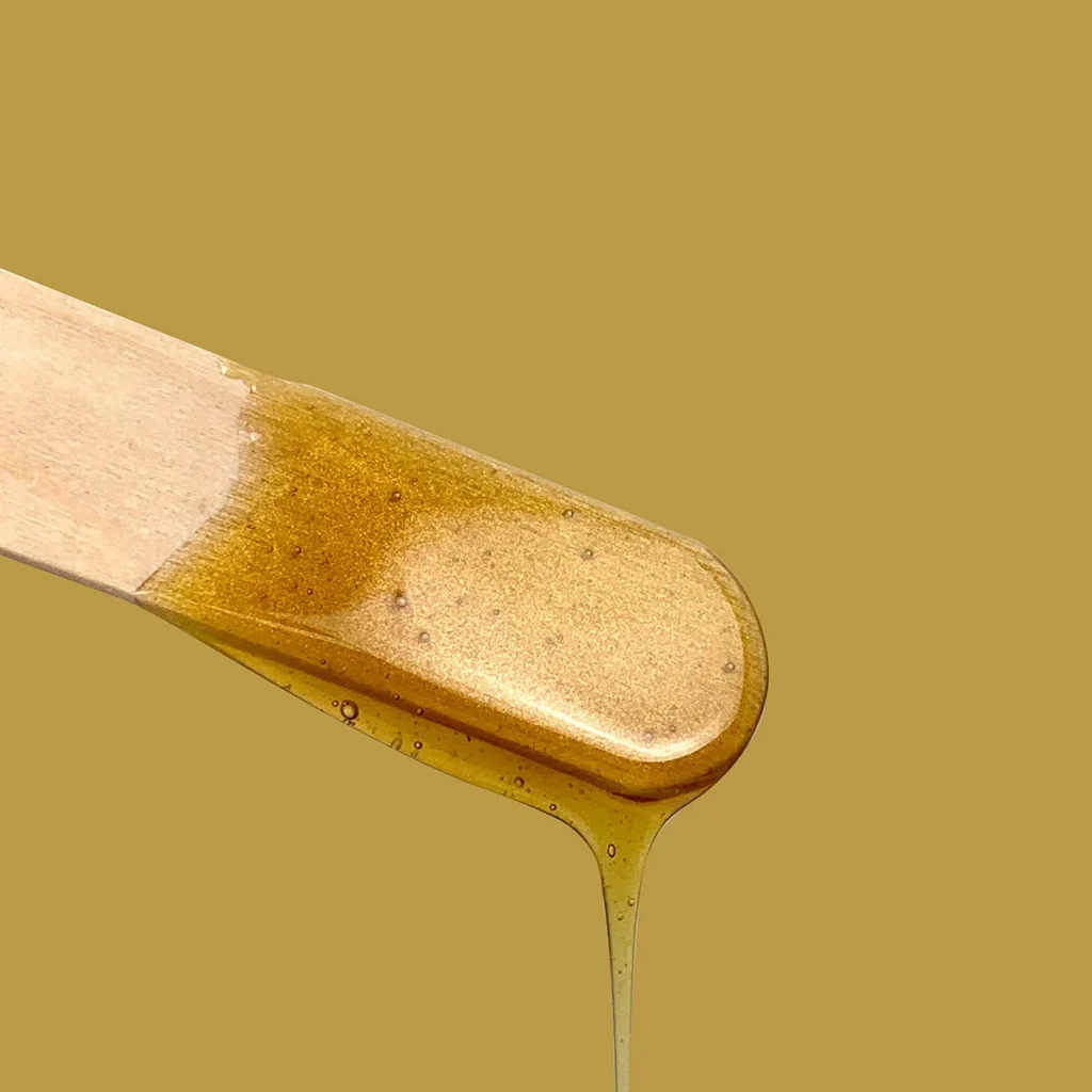 Cire chaude Perron Rigot fondue coulant sur une spatule d’épilation professionnelle
